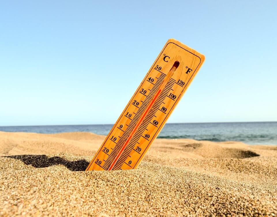 A selective focus shot of a thermometer in the beach sand with a blurred background