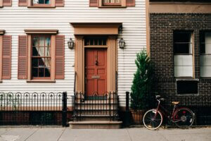 rowhouses with red front down and black iron fence, and a bike leaning against it.