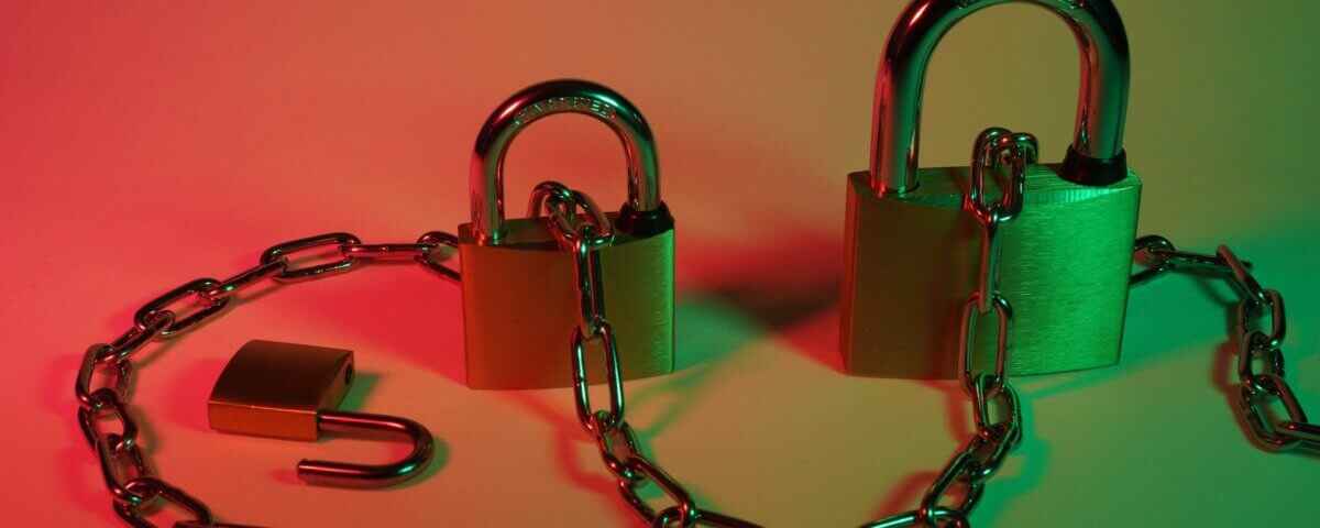 Three different size pad locks with a chain going through them on a red and green background.